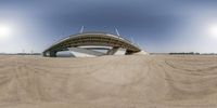 view of a wide angle shot of a bridge going over a beach area in the daytime