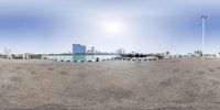 an image of a very wide sandy beach in the ocean with boats on it and many buildings in the distance