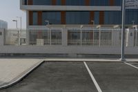 a white fence around a parking lot in front of some buildings and a car parked