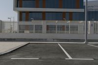 a white fence around a parking lot in front of some buildings and a car parked