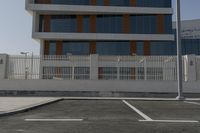 a white fence around a parking lot in front of some buildings and a car parked