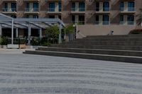 a building behind a park and some steps and a bike path with a umbrella on it