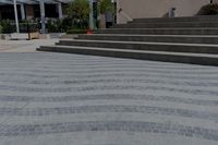 a building behind a park and some steps and a bike path with a umbrella on it