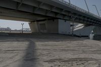 the shadow of a person on a skateboard underneath a bridge, a city in the background