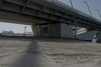 the shadow of a person on a skateboard underneath a bridge, a city in the background