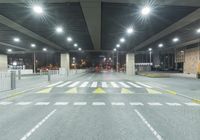 an empty street with lots of lights on the overhead ceiling in a building area at night