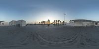 two white buildings sitting on top of a sandy beach near the ocean under a clear sky