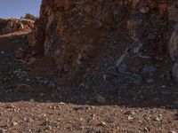 a red motorcycle riding on the rocky road near a hill of rocks and a person