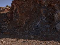 a red motorcycle riding on the rocky road near a hill of rocks and a person