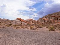 a dry desert landscape in the middle of a valley with rocks and brush, clouds in the background