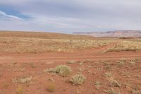 a dirt road with the word land of the west, in front of a desert landscape