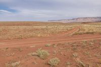 a dirt road with the word land of the west, in front of a desert landscape