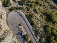 an aerial shot looking down at the road winding up a slope near a valley and mountain side