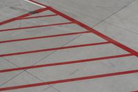 a plane on the runway at an airport in france as the red stripe is painted on the concrete