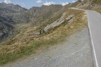 a motorcycle is driving down a winding road in the middle of mountains on an extremely sunny day