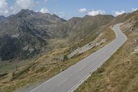 a motorcycle is driving down a winding road in the middle of mountains on an extremely sunny day