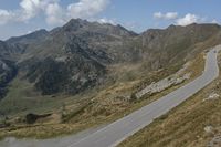 a motorcycle is driving down a winding road in the middle of mountains on an extremely sunny day