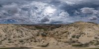 some big rocks under cloudy skies and clouds with a person on a bicycle walking along it