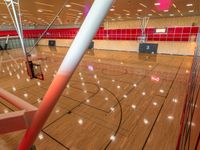 basketball court inside the building with many lights on it and the basketball hoop near the wall