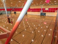 basketball court inside the building with many lights on it and the basketball hoop near the wall