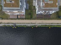 an aerial shot of some houses near the water, with canoes parked along one side and a parking lot on the other side