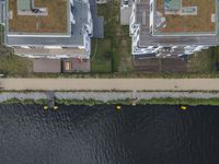 an aerial shot of some houses near the water, with canoes parked along one side and a parking lot on the other side