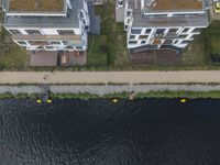 an aerial shot of some houses near the water, with canoes parked along one side and a parking lot on the other side