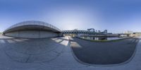 a view of a city and bridge from a fish eye lens at the end of a skateboarding course