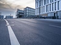 a city street with some cars parked and the building is next to it and clouds are flying in the sky