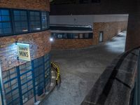 some dark blue windows in an industrial building with no one on the street to the right