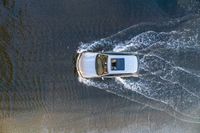 a boat in the water next to another car in the ocean in mid air view