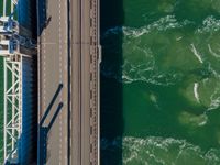 this is an overhead view of the river and bridge that connects to the bridge, where cars are traveling