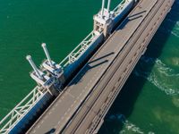 the view from above of an aerial shot of a bridge on the water with two large ships