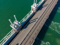 the view from above of an aerial shot of a bridge on the water with two large ships