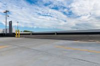 a parking lot filled with lots of parking space next to a building and the blue sky