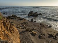 a grassy field by the shore and a cliff with rocks in the ocean in the background