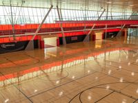 inside a gym with a wooden floor and multiple tall windows that provide light and ventilation