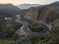 a curve highway in the hills with many lanes going through it at sunrise light and sun setting