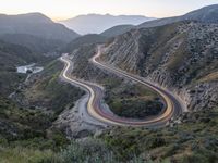 a curve highway in the hills with many lanes going through it at sunrise light and sun setting