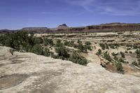 a scenic scene shows the valley with barren terrain in the background of red and green mountains