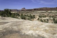 a scenic scene shows the valley with barren terrain in the background of red and green mountains