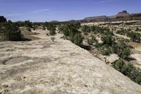 a scenic scene shows the valley with barren terrain in the background of red and green mountains