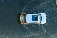 an overhead view of a car driving through the waves on a beach in front of a car