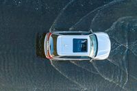 an overhead view of a car driving through the waves on a beach in front of a car