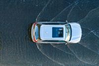 an overhead view of a car driving through the waves on a beach in front of a car