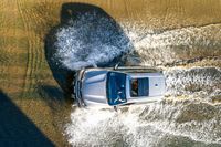 an aerial view of a car driving down some water on a road in the middle of the day