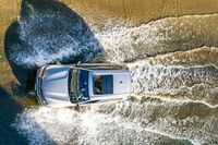 an aerial view of a car driving down some water on a road in the middle of the day