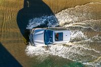 an aerial view of a car driving down some water on a road in the middle of the day