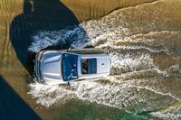 an aerial view of a car driving down some water on a road in the middle of the day