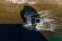 a car driving through the water in the ocean from above the side of a boat